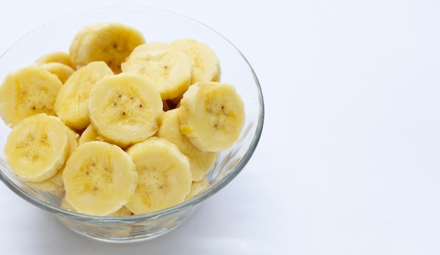 Tranches de banane dans un bol en verre sur fond blanc.