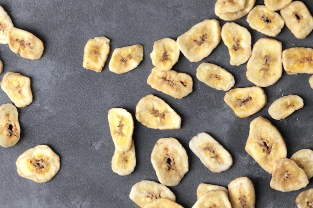 Tranches de banane sucrée sur fond gris, vue de dessus avec un espace pour le texte. Fruits secs comme collation saine