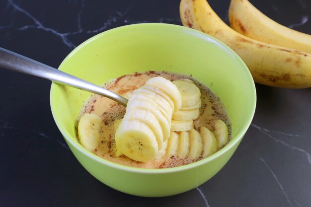 Tranches de bananes mûres fraîches dans le mélange pour la cuisson du pouding au pain aux bananes