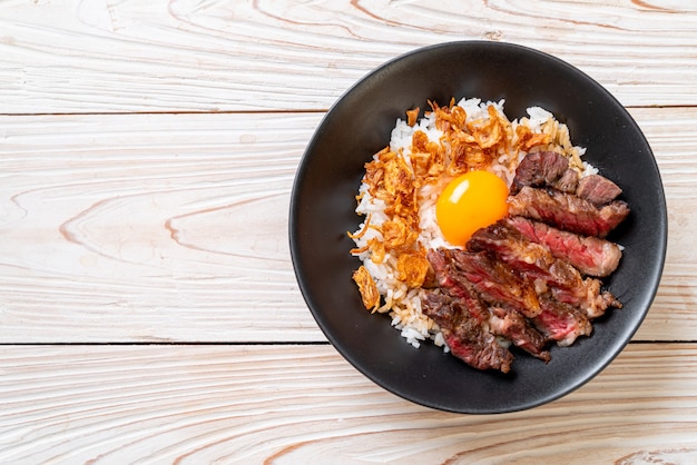 tranches de boeuf sur un bol de riz garni d'oeuf