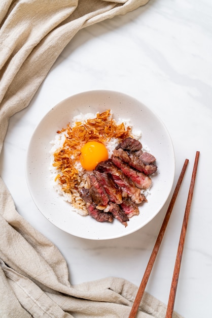 tranches de boeuf sur un bol de riz garni d'oeuf