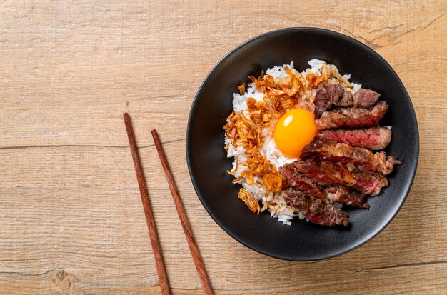 tranches de boeuf sur un bol de riz garni d'oeuf