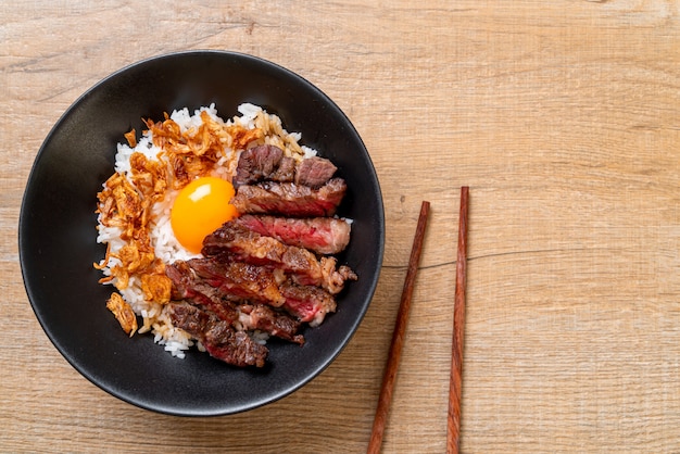 tranches de boeuf sur un bol de riz garni d'oeuf