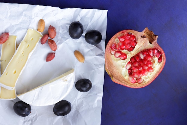 Tranches de camembert aux noix et fruits sur papier parchemin sur fond bleu Un excellent produit pour un petit-déjeuner Gros plan