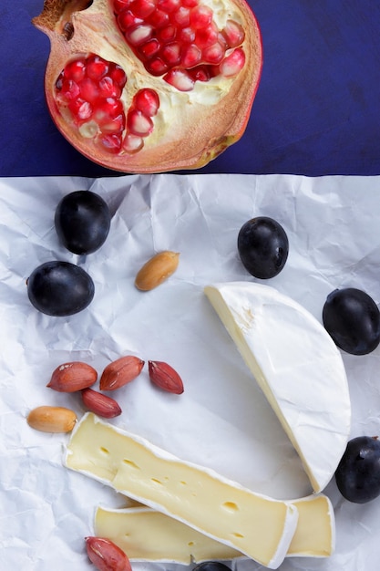 Tranches de camembert aux noix et fruits sur papier parchemin sur fond bleu Un excellent produit pour un petit-déjeuner Gros plan