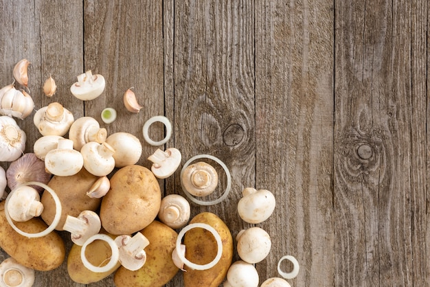 Tranches de champignons et pommes de terre sur une table en bois.