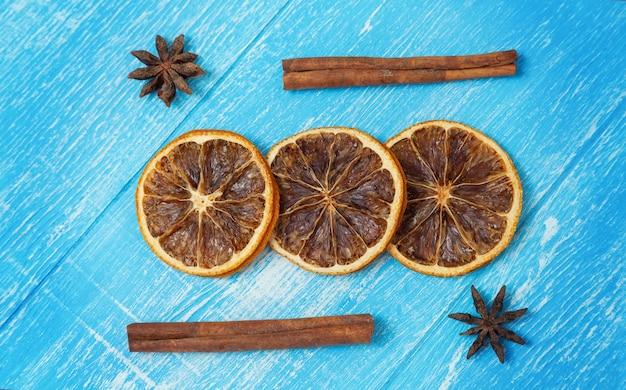 Tranches de citron, cannelle et anis séchées reposent sur un bois bleu.