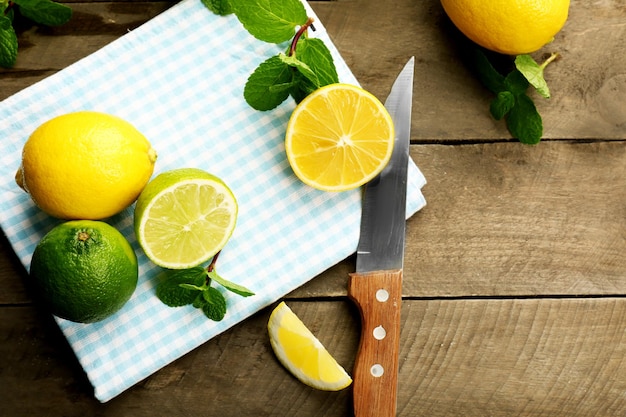 Tranches de citron frais et citron vert avec un couteau sur la vue de dessus de table en bois