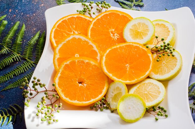 Photo tranches de citron et d'orange sur une grande assiette en céramique blanche et baies de sureau