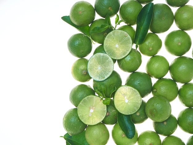 Tranches de citron vert avec des feuilles sur fond blanc