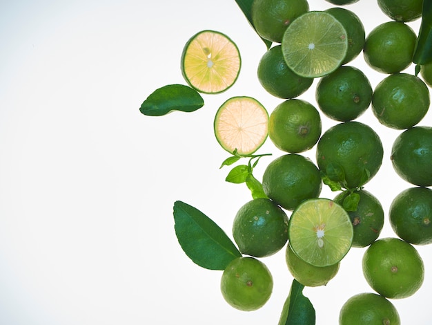 Tranches de citron vert avec des feuilles sur fond blanc