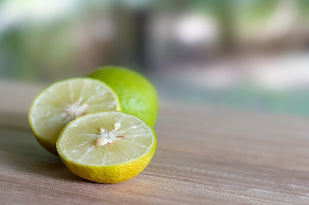 Tranches de citron vert placées sur des planches en bois avec fond de nature.