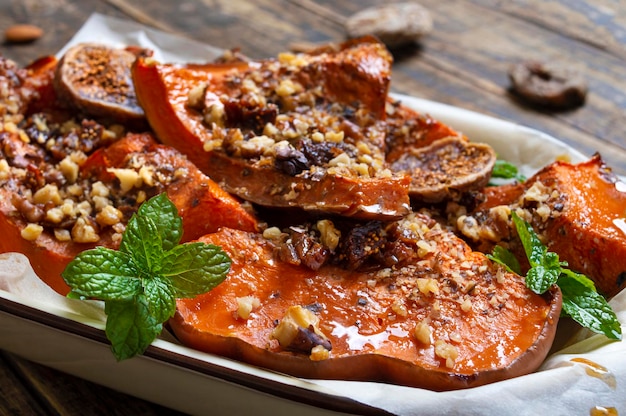 Tranches de citrouille au four avec noix, miel et fruits secs sur un fond en bois. Fermer. Une bonne nutrition, repas diététique. Concept de valeur nutritionnelle des légumes.