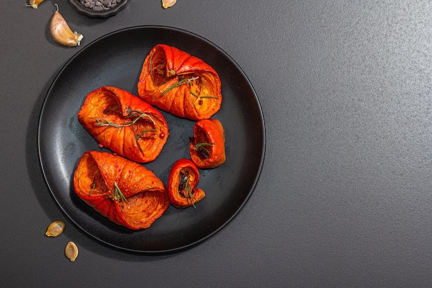 Tranches de citrouille cuites au four avec du miel, des épices et des graines Nourriture végétalienne saine à la mode lumière dure ombre noire Fond en béton de pierre noire vue de dessus