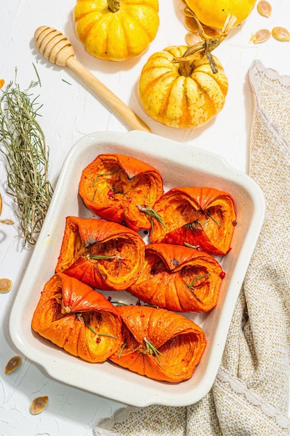 Tranches de citrouille cuites au four avec du miel et des graines de romarin Nourriture végétalienne saine à la mode lumière dure ombre sombre Fond blanc plat vue de dessus