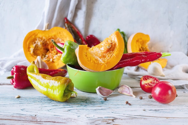 Tranches de citrouille et légumes frais mûrs assortis pour préparer le dîner sur une table rustique en bois