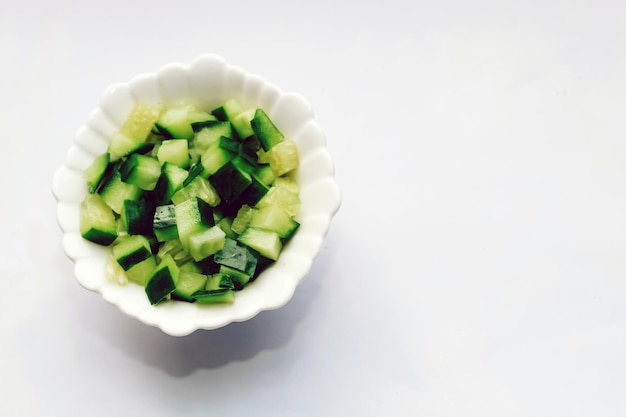 Tranches de concombre dans un cube pour salade dans une assiette sur un tableau blanc