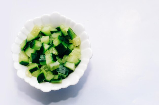 Tranches de concombre dans un cube pour salade dans une assiette sur un tableau blanc