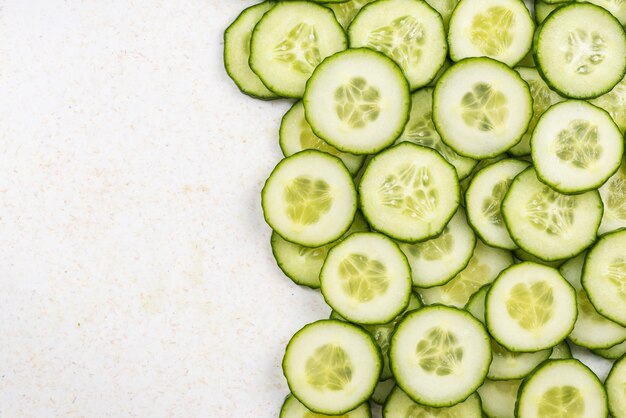 Tranches de concombre fond de bordure alimentaire sur marbre blanc