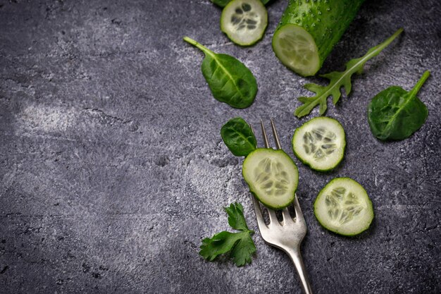 Tranches de concombre sur fourchette et feuilles d’épinards. Concept de nourriture saine. Mise au point sélective