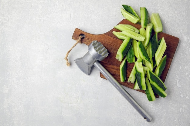 Tranches de concombres frais sur une planche à découper en bois marteau de cuisine sur une table en béton léger