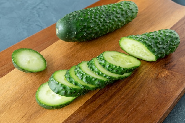 Tranches de concombres frais sur une planche à découper sur une surface sombre