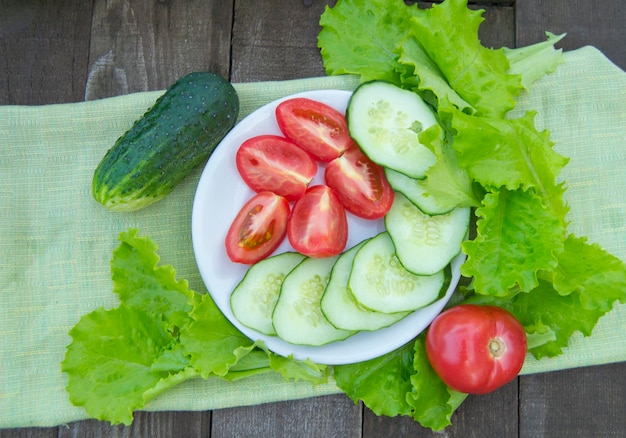 Tranches de concombres et de tomates avec de la laitue sur une vieille table en bois