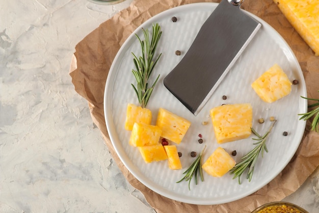 Tranches de délicieux fromage marbré avec un brin de romarin et un couteau à fromage sur une assiette sur fond de béton clair. vue de dessus