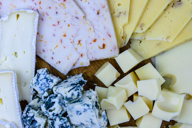 Tranches de différents types de fromage sur un fond en bois. Plateau à fromage