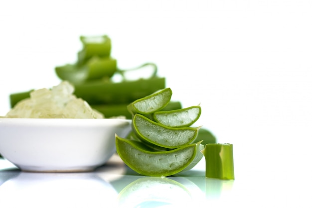 Photo des tranches de feuilles d'aloe vera et du gel d'aloe vera dans un bol. l'aloe vera est une phytothérapie très utile pour les soins de la peau et des cheveux.