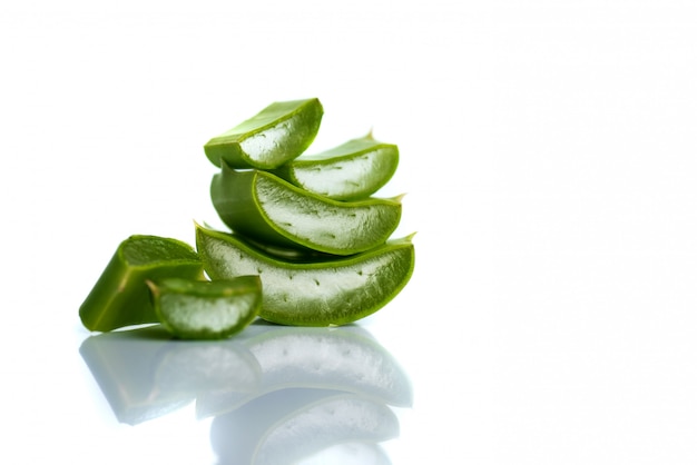 Tranches de feuilles d'Aloe Vera sur une surface blanche. L'Aloe Vera est une phytothérapie très utile pour les soins de la peau et des cheveux.