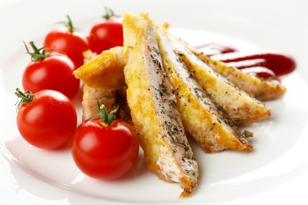 Photo tranches de filet de poulet avec sauce et tomate cerise sur plaque close up