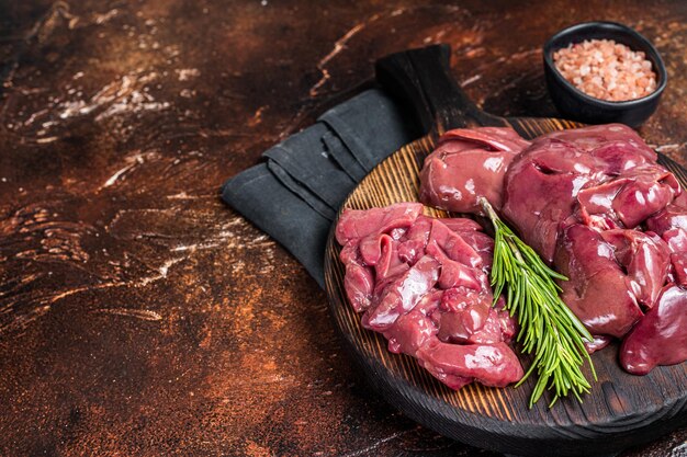 Tranches de foie de poulet cru abats de volaille frais sur planche de bois Fond sombre Vue de dessus Espace de copie