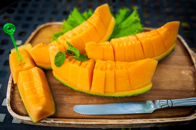 Tranches fraîches de melon sucré orange mis sur une plaque en bois.