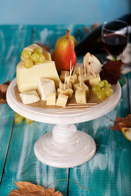 Photo tranches de fromage, poire et raisins sur un support en bois. fermer