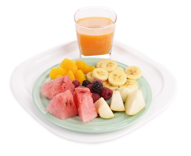 Tranches de fruits aux baies sur assiette et verre de jus isolé sur blanc