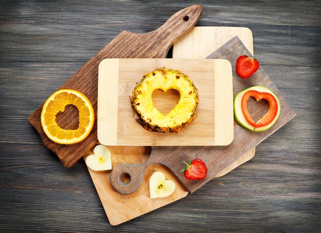 Tranches de fruits avec coupe en forme de coeur et de baies sur table close up