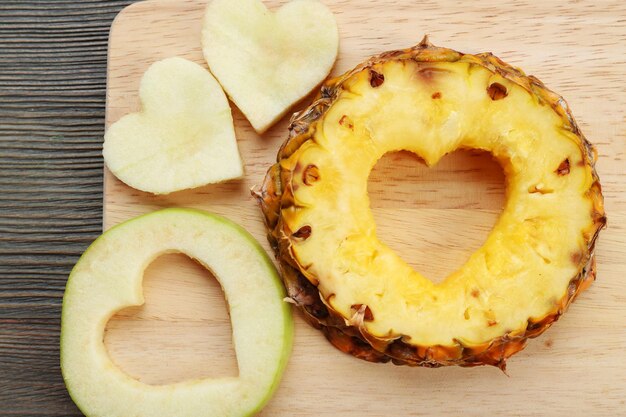 Tranches de fruits avec coupe en forme de coeur sur fond de bois