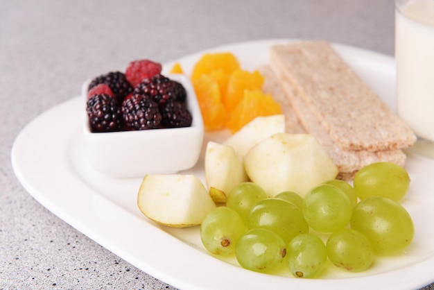 Tranches de fruits avec des pains croustillants et un verre de lait sur une assiette sur une table en gros plan