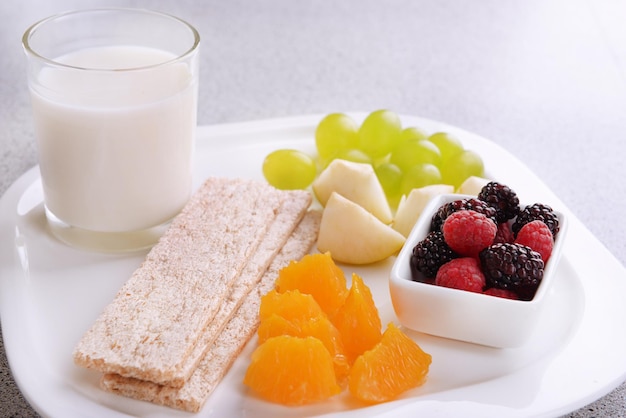 Tranches de fruits avec des pains croustillants et un verre de lait sur une assiette sur une table en gros plan