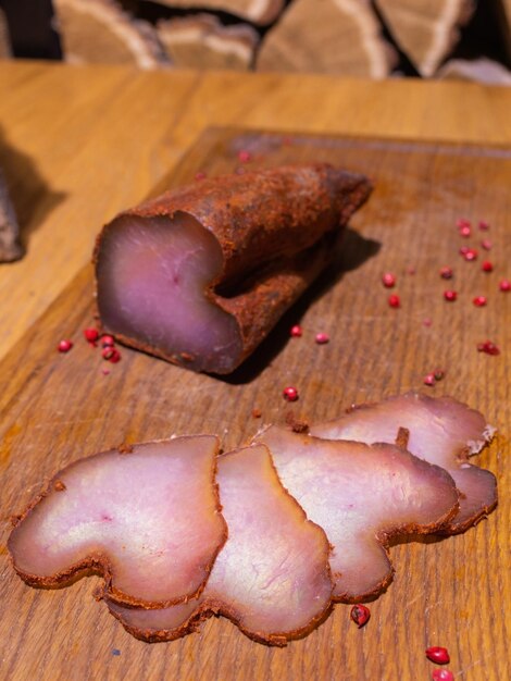 Tranches de gammon fumé sur une table en bois avec ajout d'herbes fraîches et d'épices aromatiques