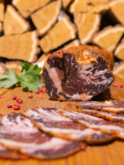 Tranches de gammon fumé sur une table en bois avec ajout d'herbes fraîches et d'épices aromatiques