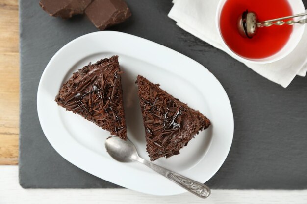 Tranches de gâteau au chocolat sur plaque sur fond de table en bois