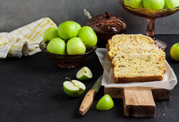 Tranches de gâteau aux pommes et à la noix de coco sur une planche à découper en bois sur fond sombre