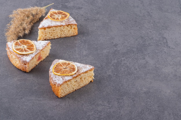 Tranches de gâteau frais avec des tranches de citron séchées sur une surface grise