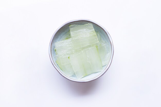 Tranches de gel d’aloe vera dans un bol en céramique blanc.