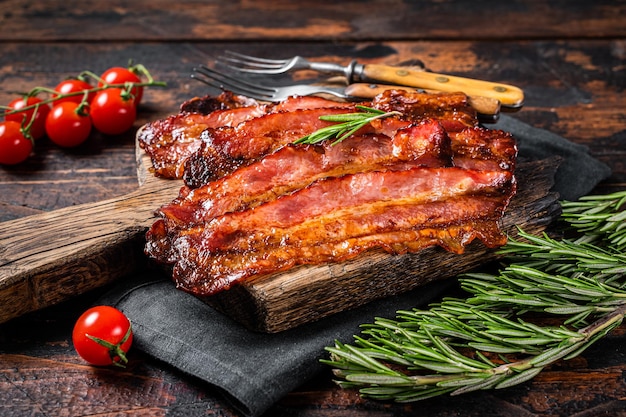 Tranches de grésillement de bacon de porc rôti sur planche de bois. Fond en bois. Vue de dessus.