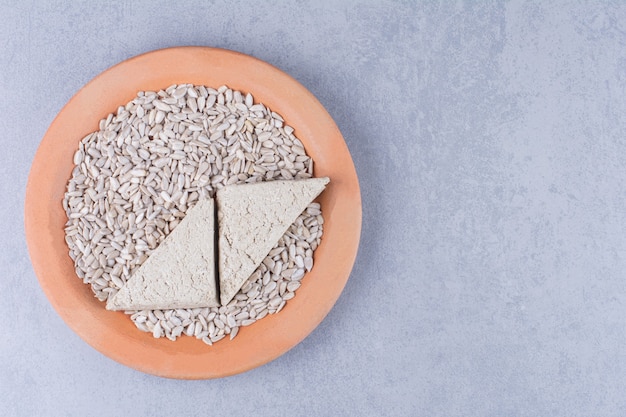 Tranches de halva de tournesol et graines pelées sur une assiette sur la surface en marbre