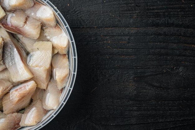 Tranches de hareng mariné à l'huile sur fond de table en bois noir vue de dessus à plat avec espace de copie pour le texte