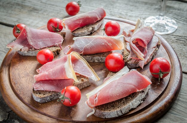 Photo tranches de jambon italien sur la planche de bois